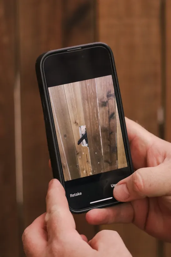 Paul photographing a customer's closed gate on his phone to send to them